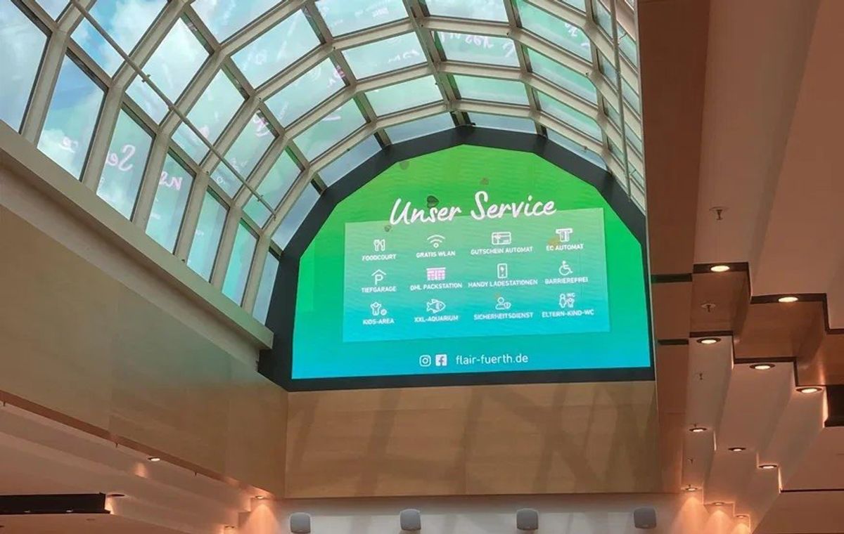 Große LED-Wand unter dem Glasdach des FLAiR Fürth zeigt die Übersicht „Unser Service“