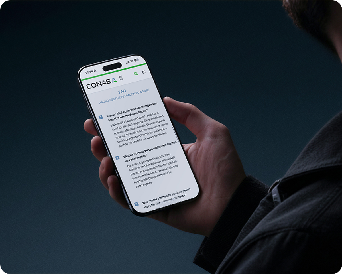 Hand hält ein Smartphone mit der FAQ-Seite der CONAE-Website zu etalbond®-Verbundplatten vor dunklem Hintergrund