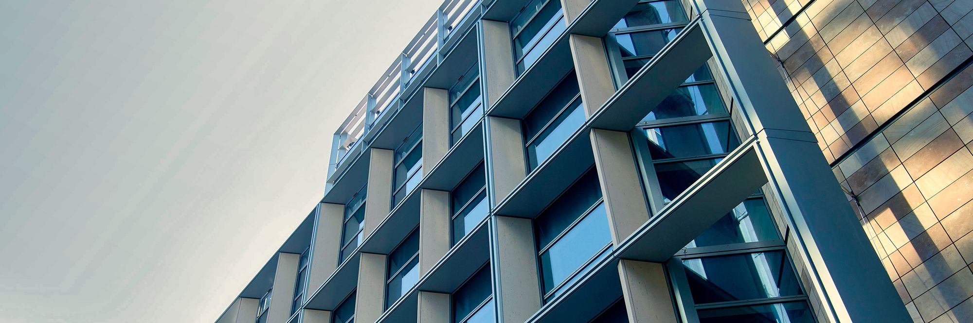 Untersicht einer modernen Bürofassade aus Glas, Sichtbeton und Metall