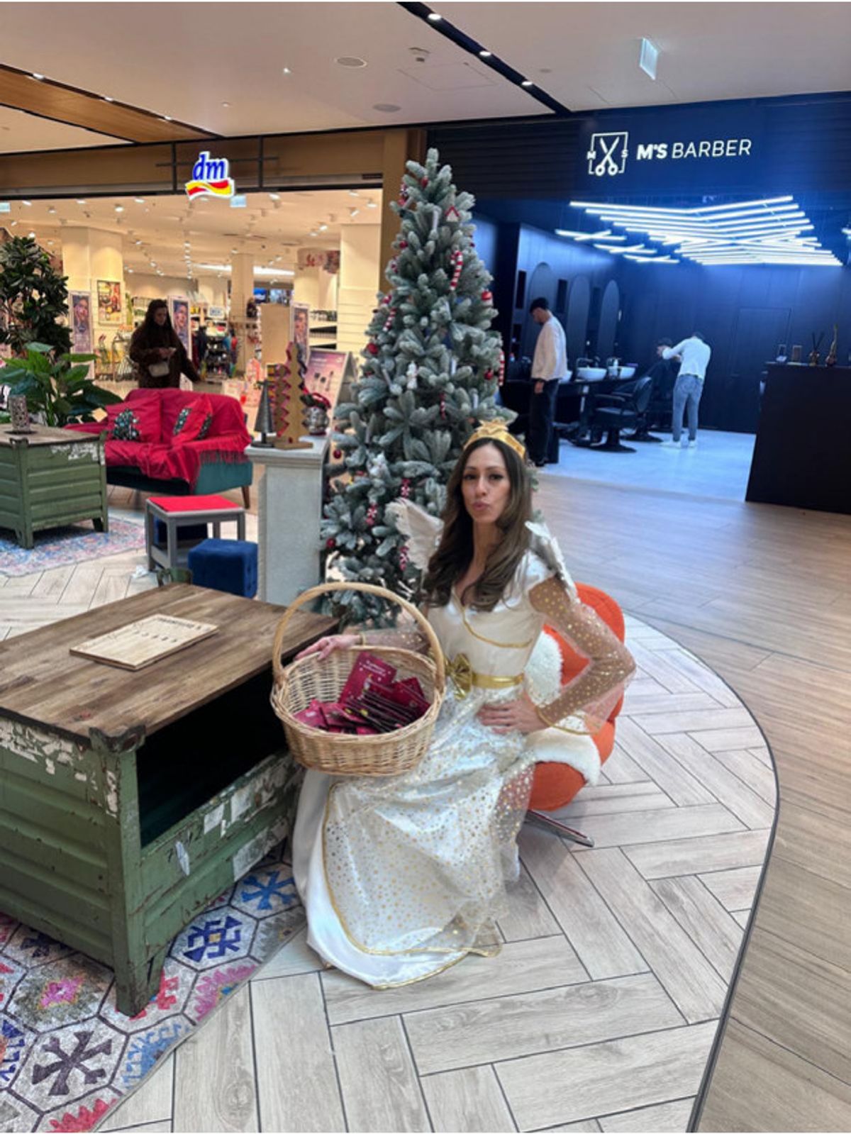 Als Weihnachtsengel verkleidete Darstellerin mit Korb voller Grußkarten neben einem Tannenbaum im FLAiR Fürth