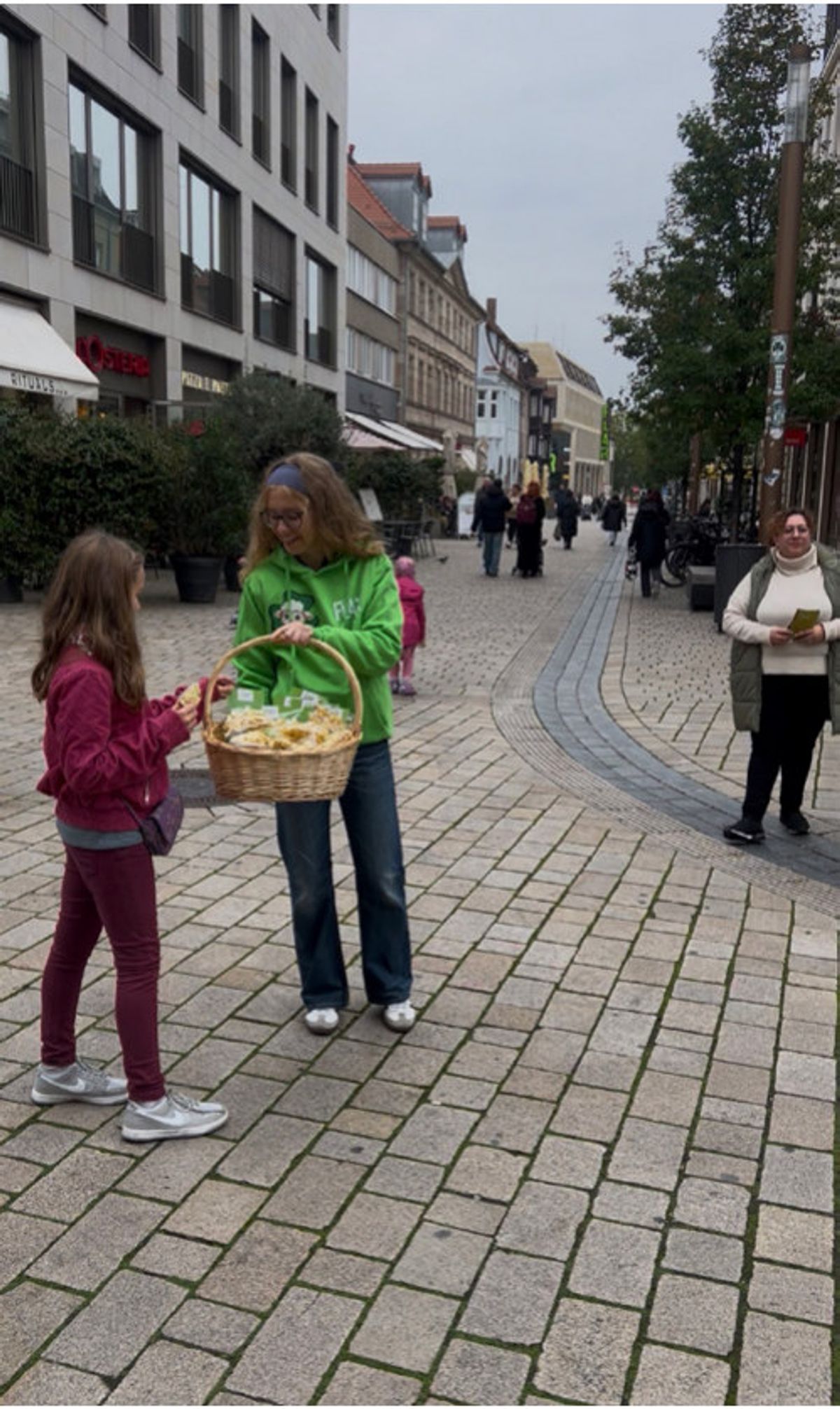 Promoterin im grünen Shirt verteilt in der Fürther Fußgängerzone Popcorn aus einem Korb