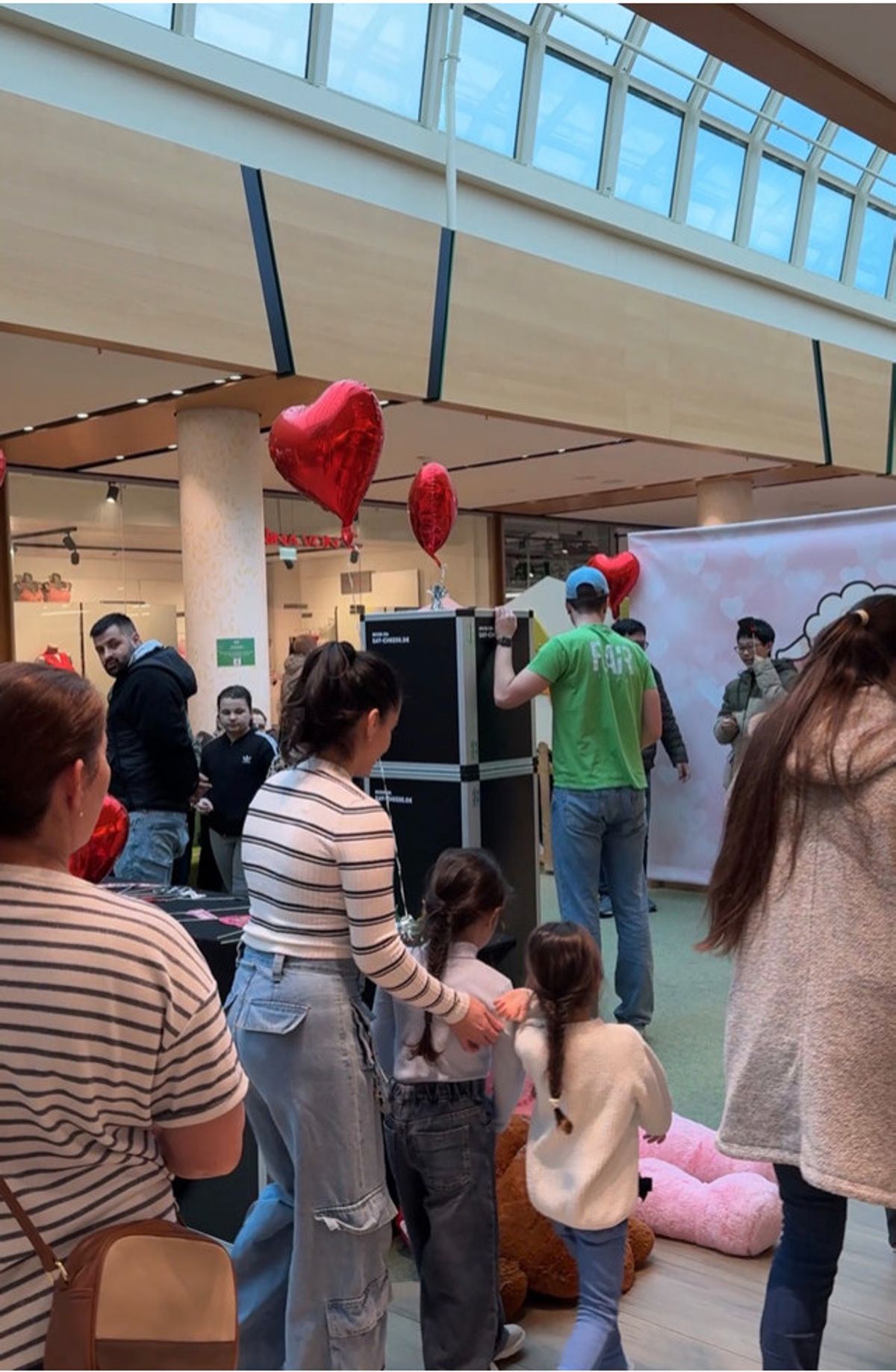 Besucher vor der Kiss-Cam-Leinwand mit roten Herzballons unter dem Glasdach des FLAiR Fürth